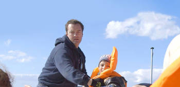 A coast guard member helps a little boy refugee on the boat